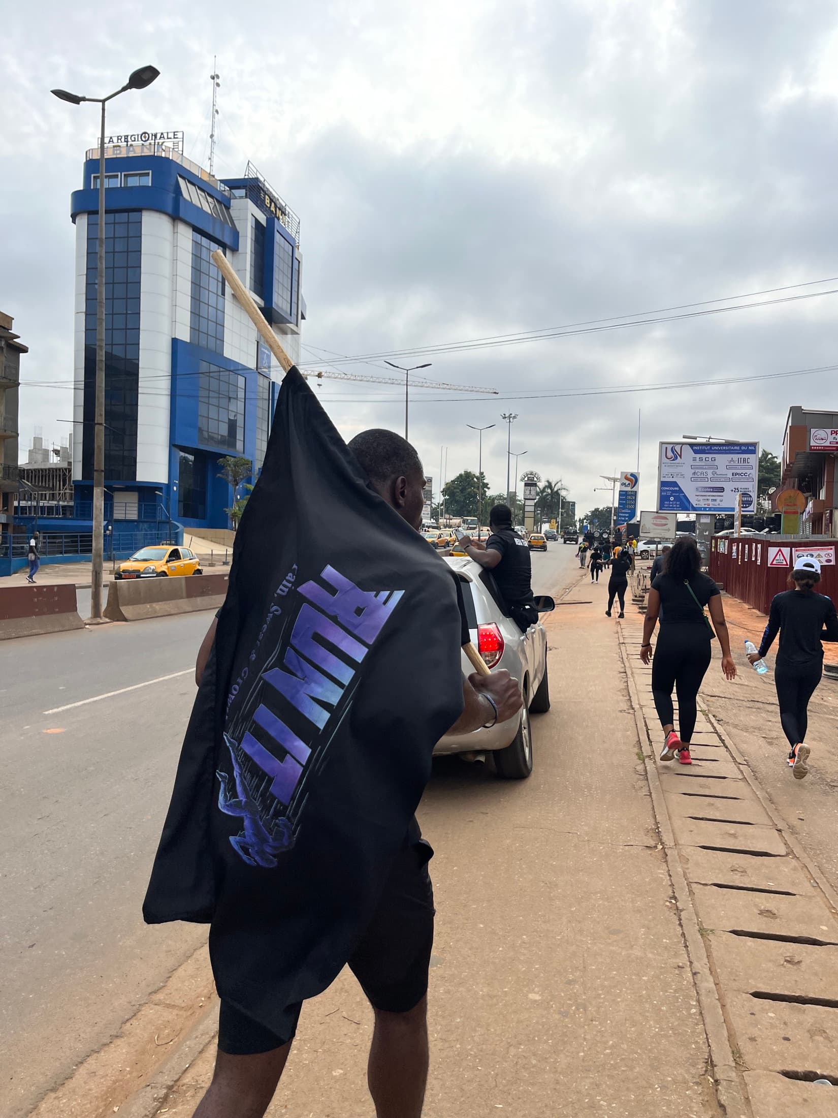 Coureur RUN IT portant le drapeau de l'événement dans les rues de Yaoundé